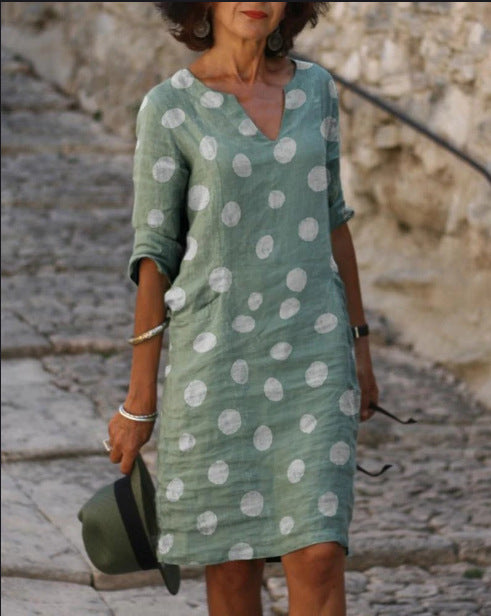 Woman wearing a green dress with white polka dots on a stone path.