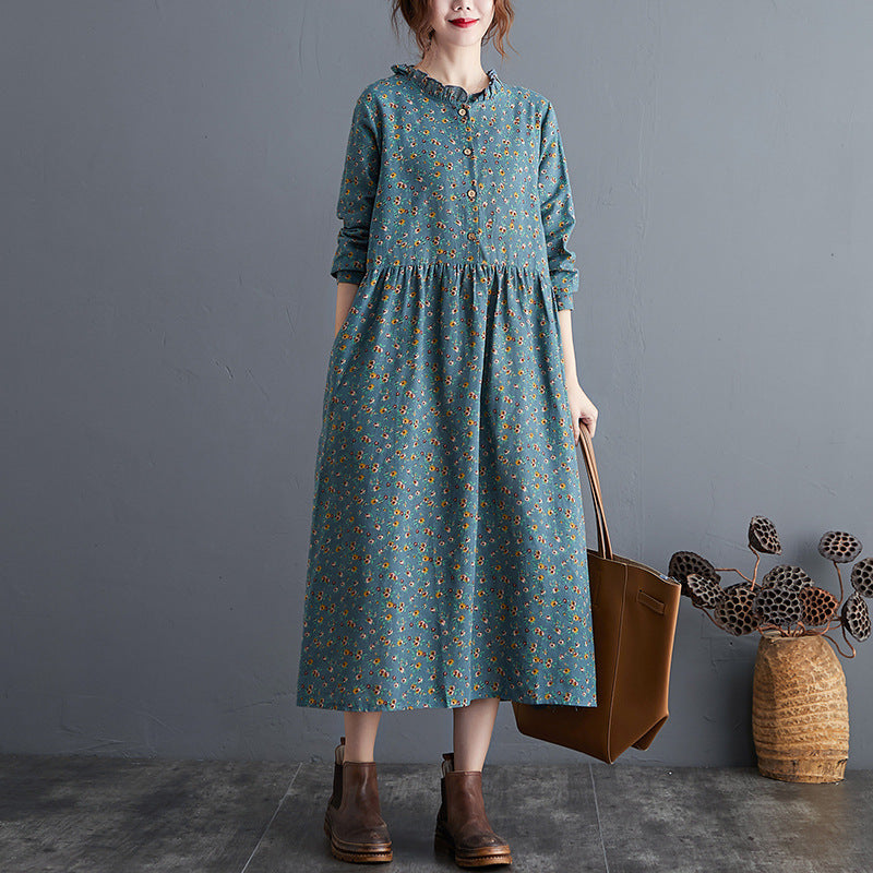 Woman wearing a blue floral dress holding a brown bag against a gray background