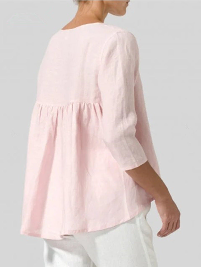 Person wearing a light pink blouse with a plain background