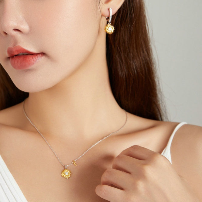Woman wearing gold earrings and necklace with a neutral background