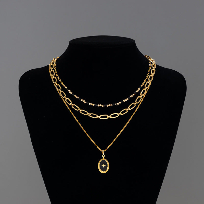 Gold chain necklaces on a black mannequin against a gray background
