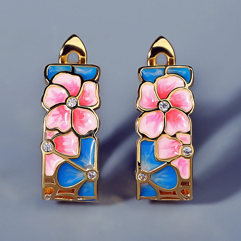 Pair of floral earrings with pink flowers and blue backgrounds on a gray background