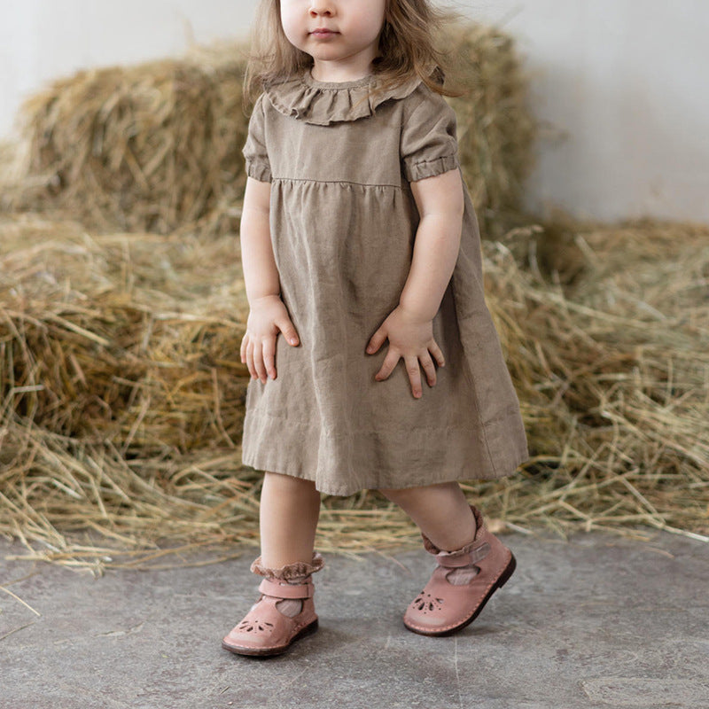 Child in a brown dress standing in front of hay bales