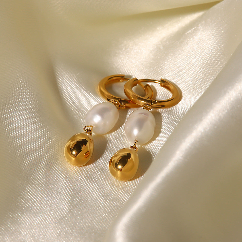 Gold hoop earrings with pearl and gold bead drops on a beige fabric background