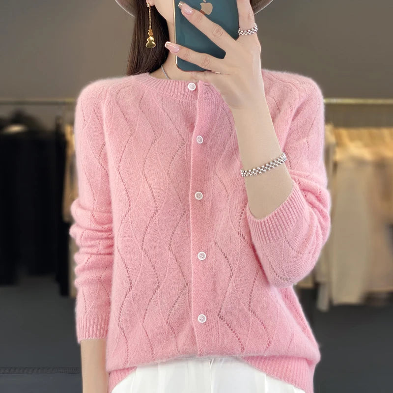 Person wearing a pink cardigan taking a mirror selfie.