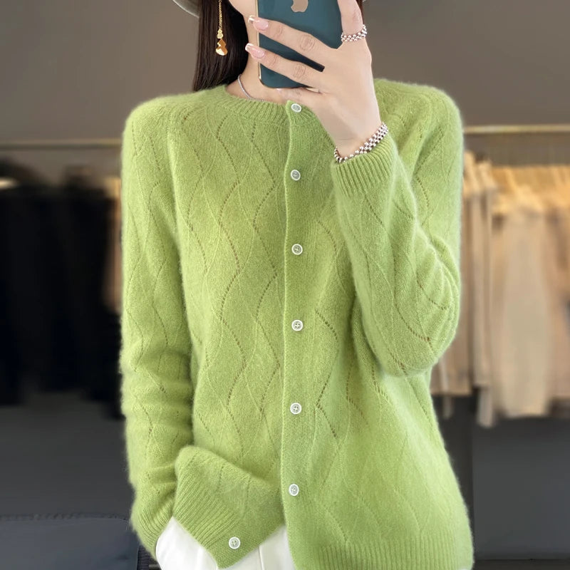 Person wearing a green knitted cardigan taking a mirror selfie.