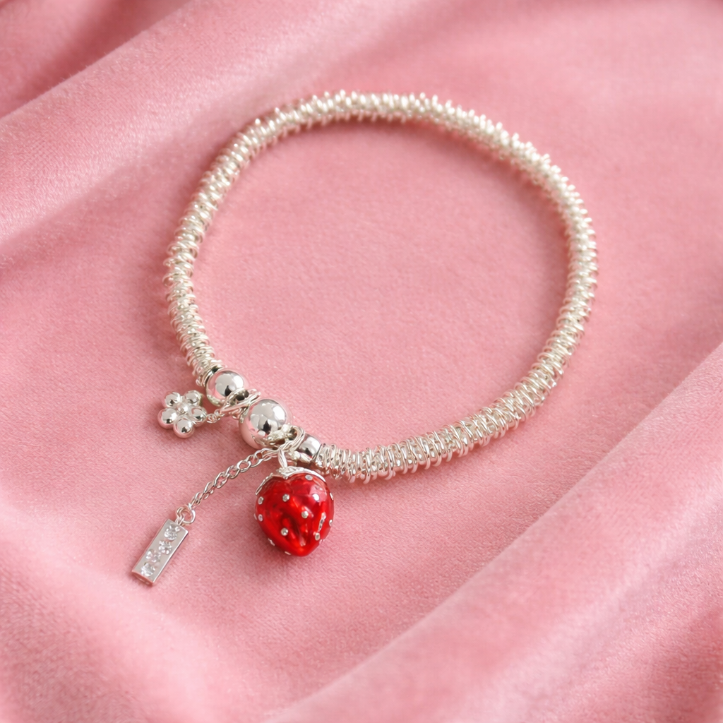 Silver-tone adjustable bracelet ring with red berry charm on neutral background