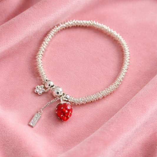Silver-tone adjustable bracelet ring with red berry charm on neutral background