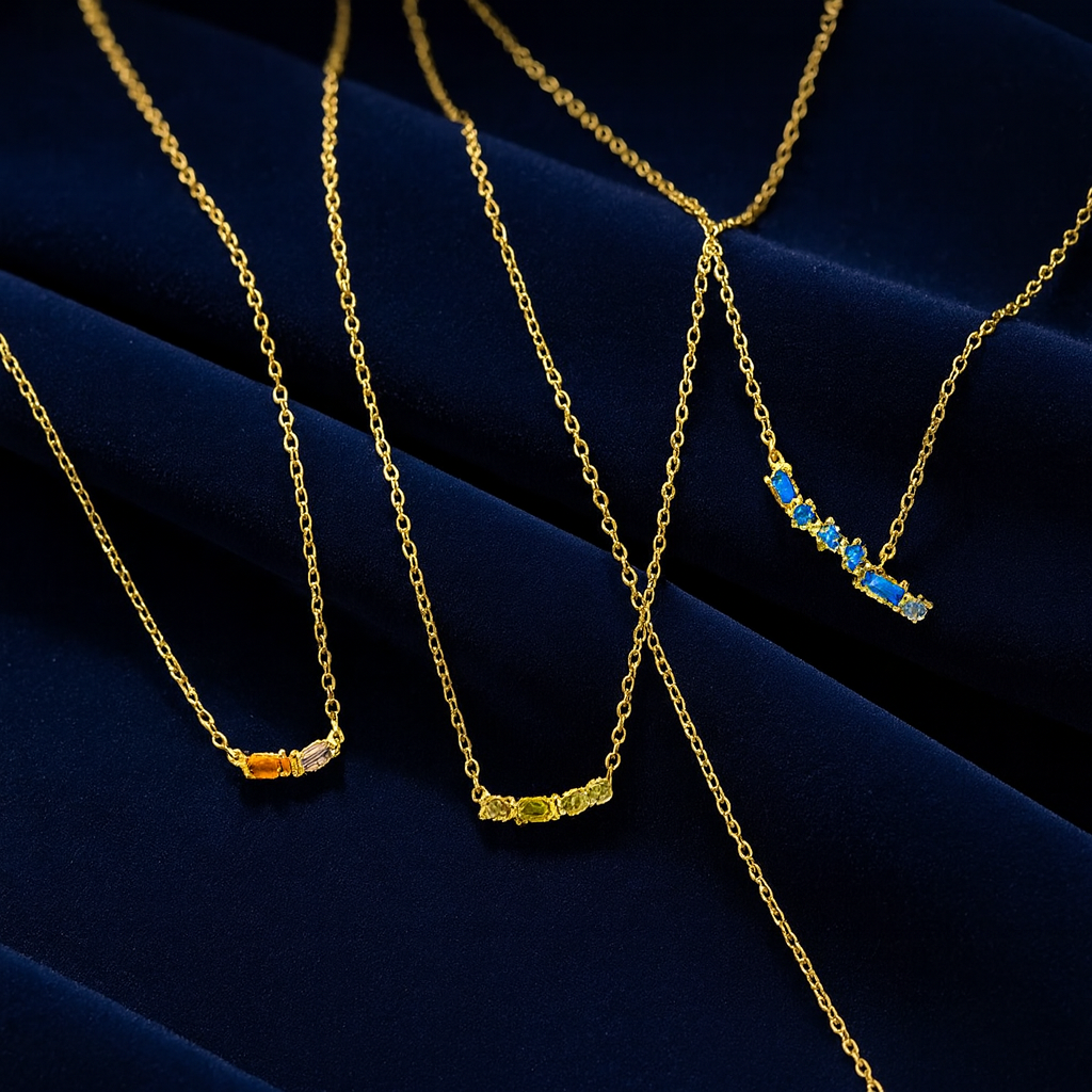 Gold necklaces with gemstone pendants on a dark blue fabric background