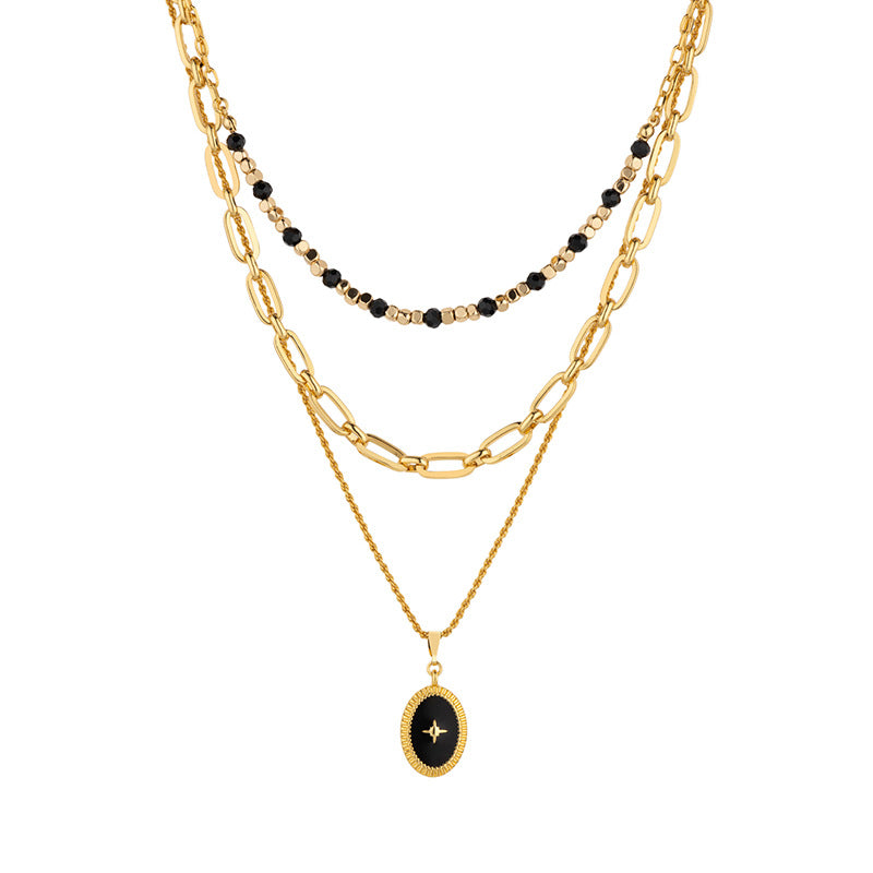 Stack of gold necklaces with black beads and a pendant on a white background