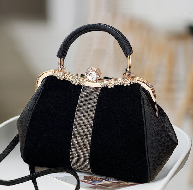 Black handbag with decorative handle and strap on a white surface